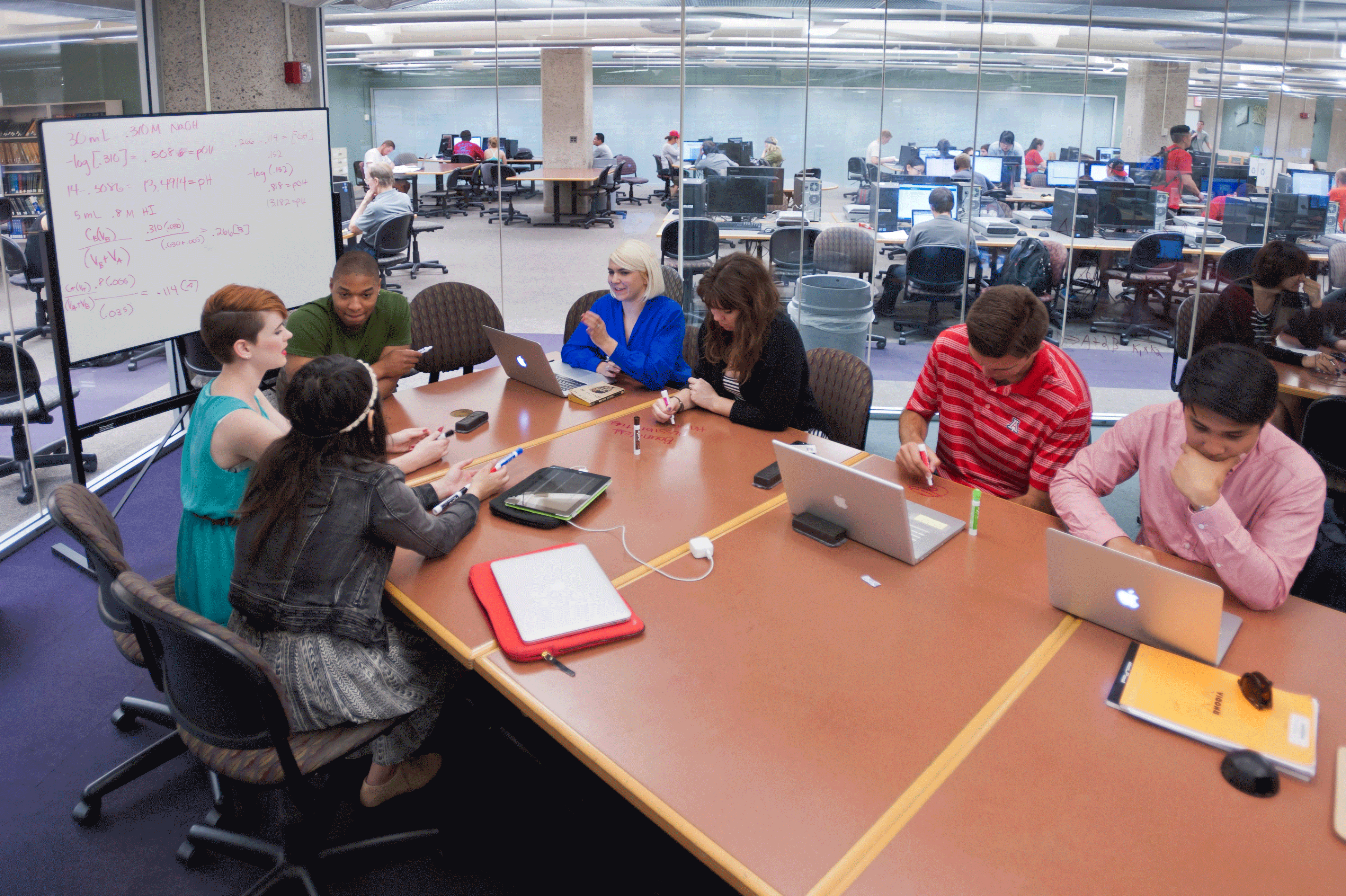 Student studying and collaborating in one of the glasswalled study rooms in the UArizona Main Library.